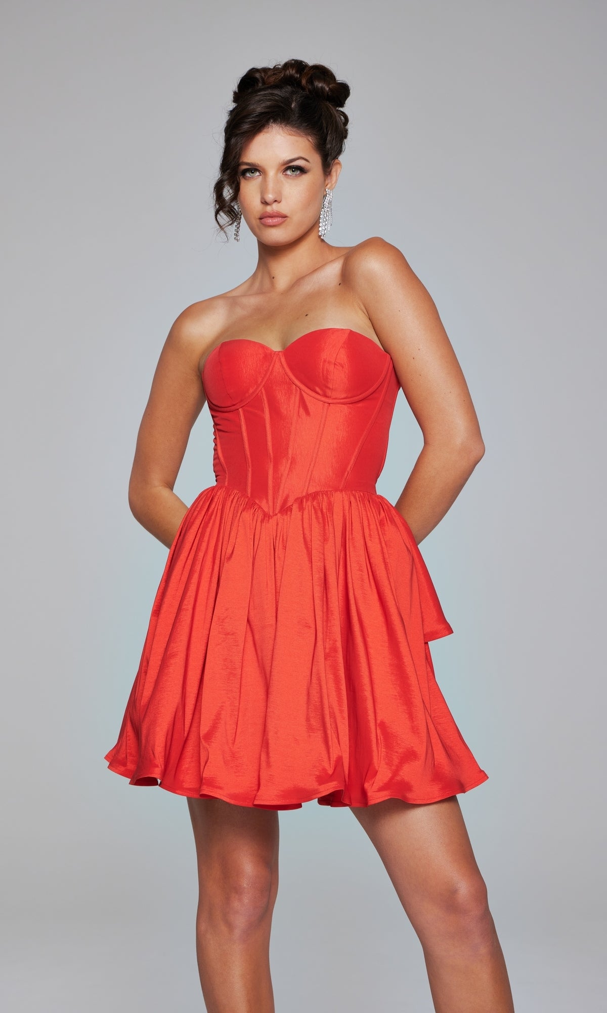 A woman models the Jovani Strapless Short Ruffled Hoco Dress 36620—a fitted red mini dress with a flared skirt—posed against a plain gray background.